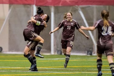 Hailey Lavarias and Amanda Wong embrace after Wong's opening goal for Manitoba. The Bisons won 5-1.